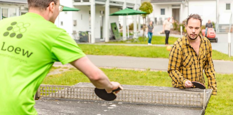Freizeitaktivität Tischtennis im Grünthaler Hof Parkstein – Dr. Loew Einrichtung Klient:innen des Grünthaler Hofs Parkstein spielen Tischtennis im Außenbereich der Einrichtung