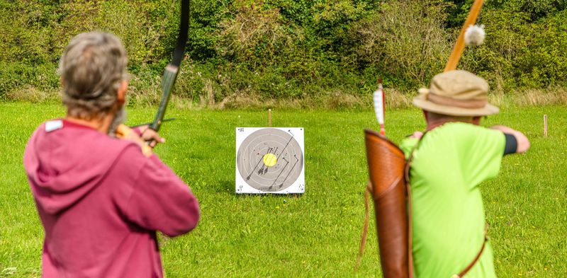 Konzentration und Bewegung beim Bogenschießen – Grünthaler Hof Parkstein, Dr. Loew Einrichtung Klient:innen des Grünthaler Hofs Parkstein schießen mit Pfeil und Bogen auf eine Zielscheibe im Gartenbereich
