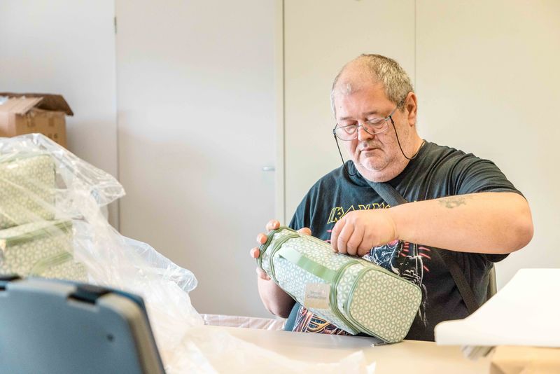 Beschäftigungsangebot: Geschenkverpackung im Grünthaler Hof Parkstein – Dr. Loew Einrichtung Klient des Grünthaler Hofs Parkstein verpackt sorgfältig ein Geschenk im Werk- oder Beschäftigungsraum