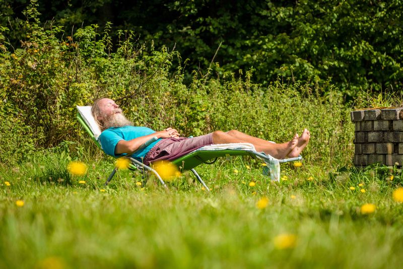 Erholung im Freien im Grünthaler Hof Parkstein – Dr. Loew Einrichtung für Menschen mit psychischen Erkrankungen Klient des Grünthaler Hofs Parkstein entspannt auf einer Liege im Garten bei sonnigem Wetter