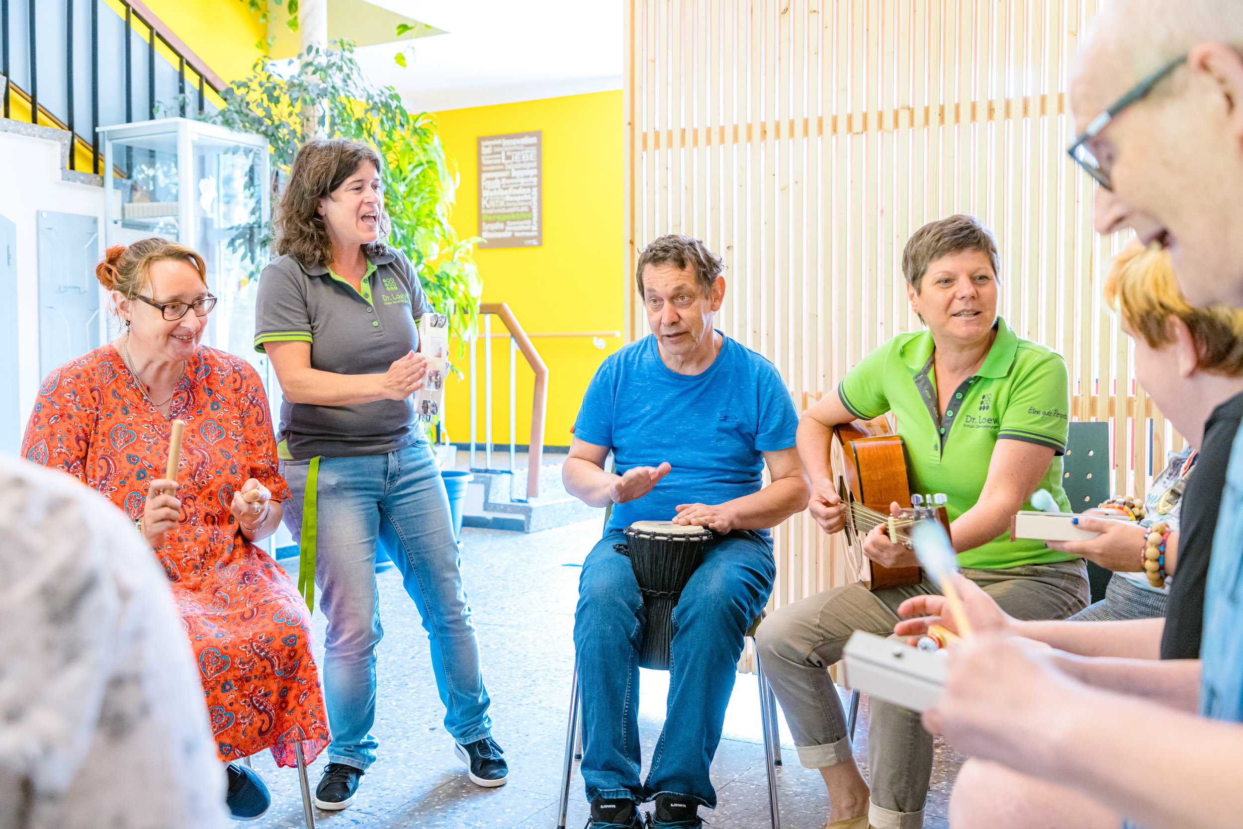 Gruppe von Menschen mit geistiger Behinderung bei einer Musiktherapie in einer Einrichtung, gemeinsam mit Betreuerinnen und Betreuern