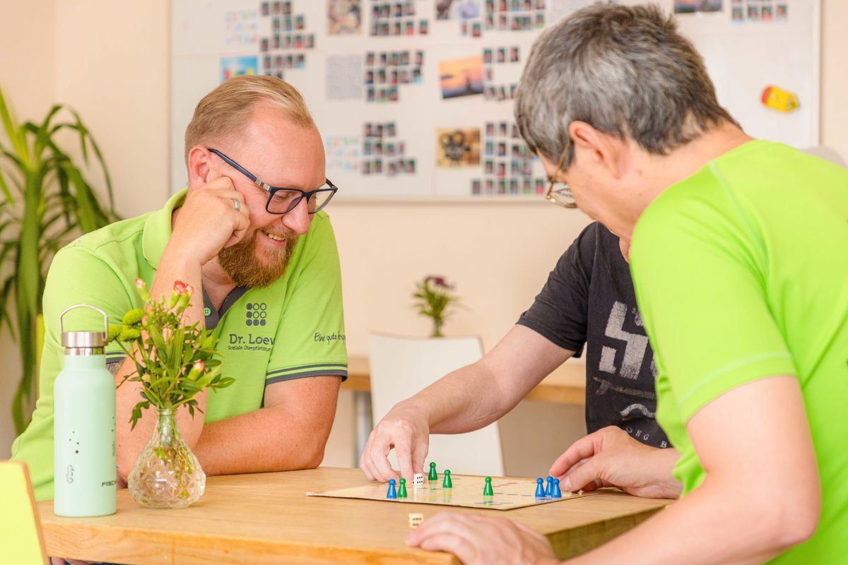 Ambulante Angebote bei Dr. Loew – Mitarbeiter spielt Gesellschaftsspiel mit Menschen mit psychischen Erkrankungen