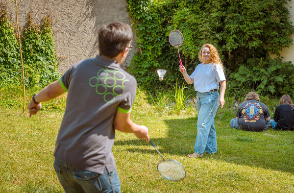 Jugendliche und Mitarbeiter beim Federballspiel auf der Gartenwiese in der Dr. Loew Einrichtung Jugendbetreuung