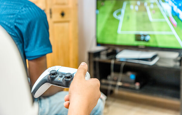 Hand mit Controller vor dem Fernseher beim Videospiel in der Dr. Loew Einrichtung Jugendbetreuung