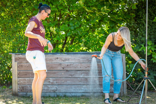 Zwei Personen beim Abkühlen mit dem Gartenschlauch im Garten der Dr. Loew Einrichtung Jugendbetreuung