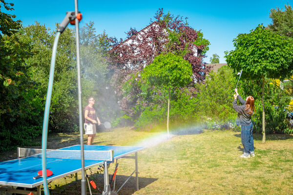 Tischtennisplatte und Rasensprenger mit Regenbogen im Garten der Dr. Loew Einrichtung Jugendbetreuung