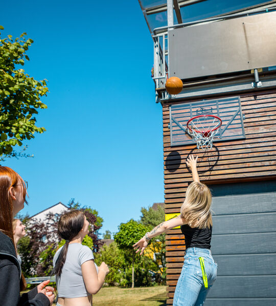 Gruppe beim Basketballspiel am Korb an der Hauswand der Dr. Loew Einrichtung Jugendbetreuung