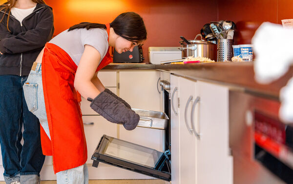 Jugendliche mit Ofenhandschuh am Backofen in der Küche der Dr. Loew Einrichtung Jugendbetreuung