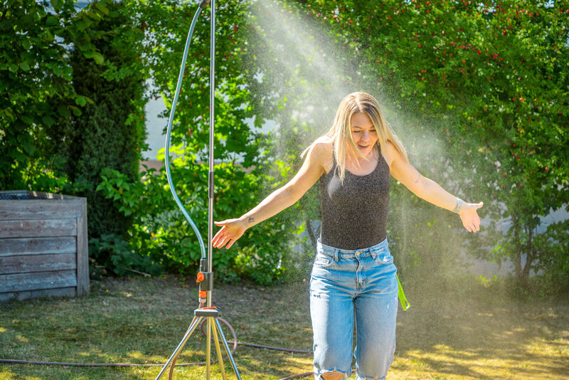 Mitarbeiterin kühlt sich an einer Gartendusche im Garten der Jugendwohngruppe Isabelle ab