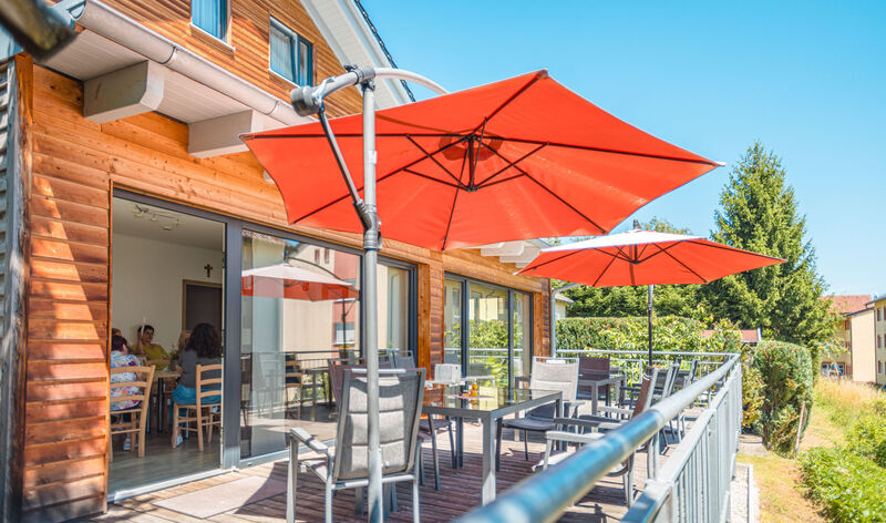 Sonnige Terrasse des Hauses Anton-Pech mit Sitzplätzen und Sonnenschirmen