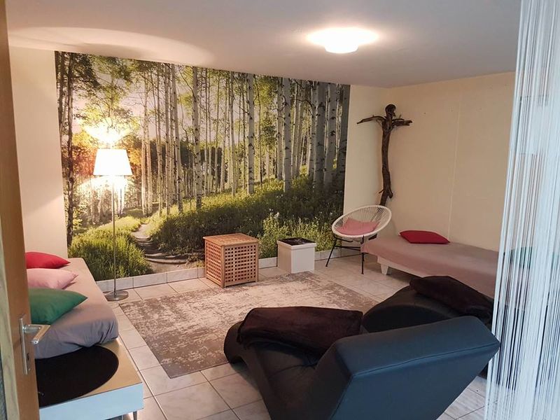 Haus Schwalbenweg – gemütlicher Wohnbereich mit Naturatmosphäre Wohnzimmer im Haus Schwalbenweg der Dr. Loew Einrichtungen mit Naturmotiv an der Wand